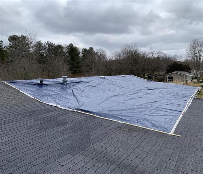 photo of a storm damaged roof after tarping