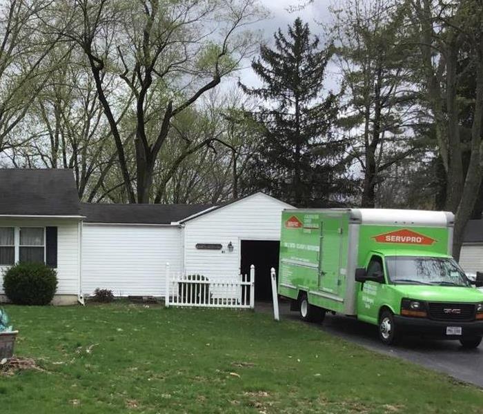 A Green SERVPRO Truck parked in front of a white ranch house.